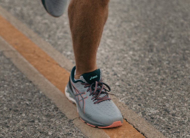 een man die op een weg rent met een paar schoenen
