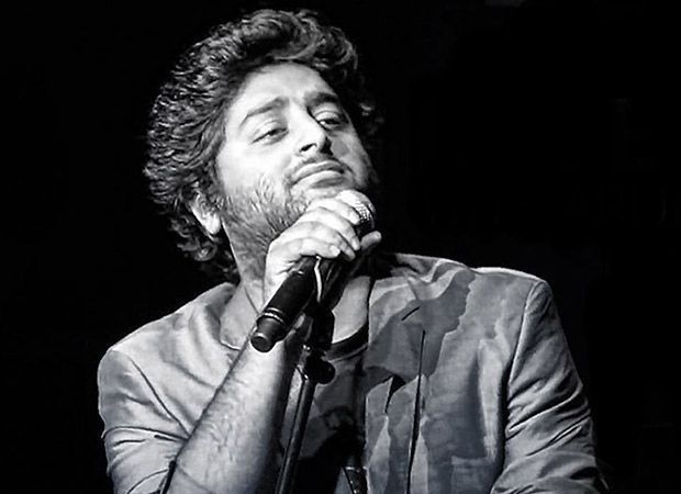 a man in a suit and tie is holding a microphone