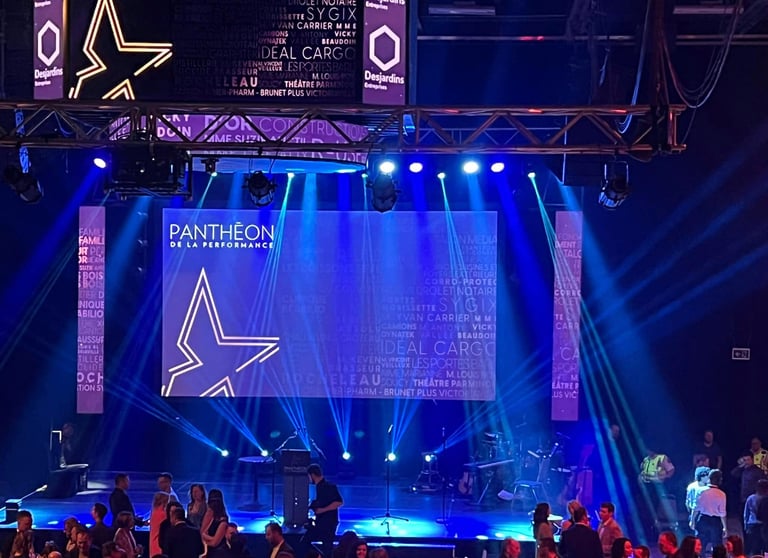 Pantheon de la Performance gala stage with blue spotlight beams and corporate sponsor logos.