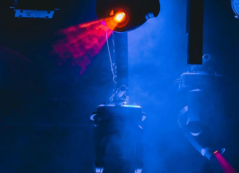 Professional stage lighting equipment casting red laser beams through blue concert fog.