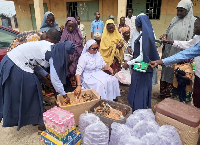 Catholic nuns and local community members distribute food and drinks during a charity relief event.