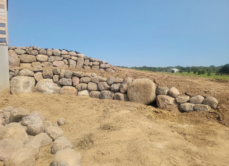 Large boulder retaining wall construction in Central MN.