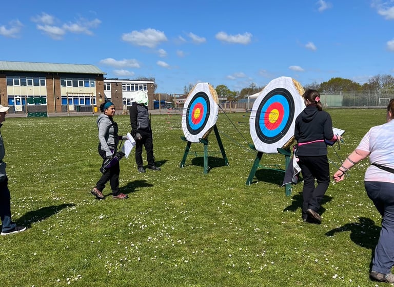 a group of people walking up to an archery target