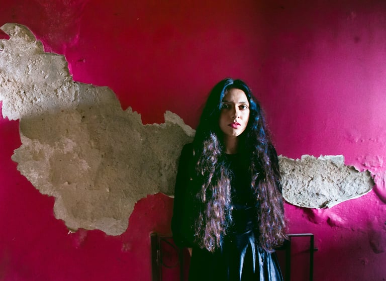 a woman in a black dress standing in front of a pink wall