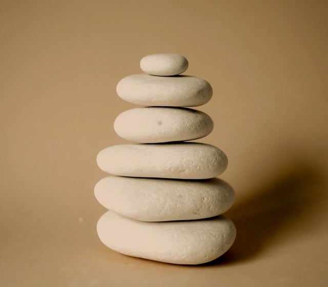 Balanced stack of smooth white zen stones for meditation and wellness on a beige background.