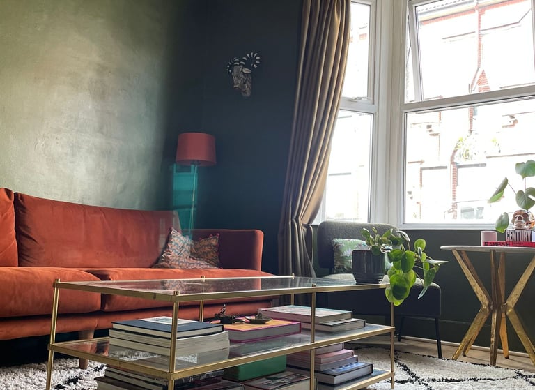 Rust sofa contrasts with deep green walls