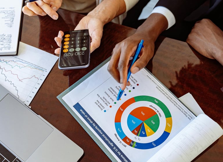 Mains de personnes en réunion pointant un graphique circulaire avec une calculatrice sur la table.