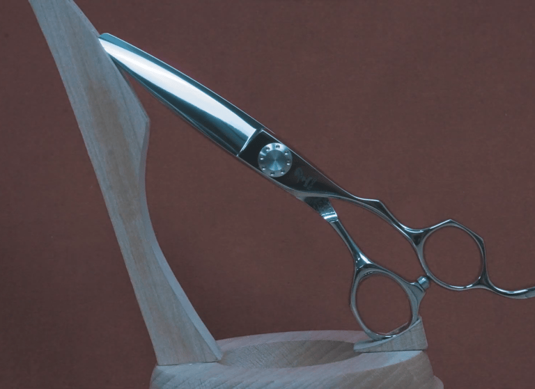 Tijeras de peluquería profesionales de acero inoxidable, exhibidas en un soporte de madera.