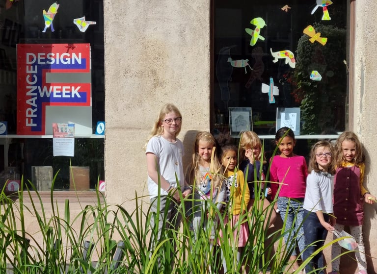 Un groupe de jeunes enfants prennent la pose devant une affiche de la France Design Week