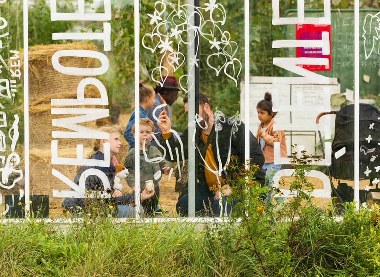 Un adulte et des enfants dessiner sur une verrière avec un feutre blanc