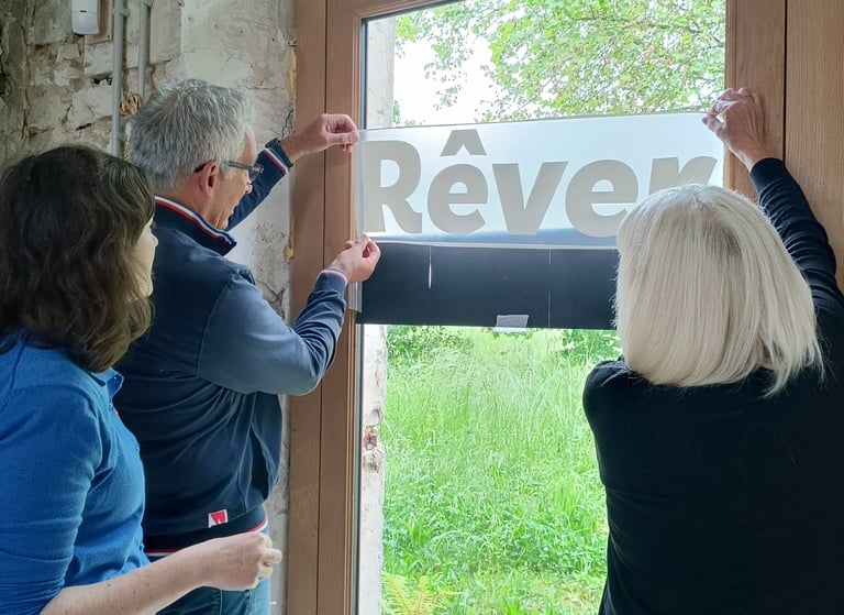 Perrine Rousselet et deux collaborateurs place le mot "Rêver" sur une porte vitrée