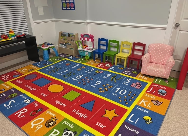Daycare playroom with colorful abc mat, chairs and reading corner