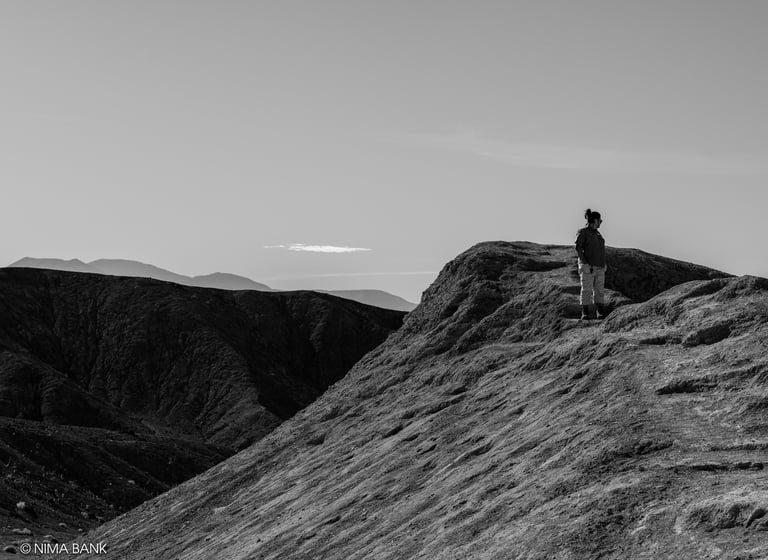 a person standing on a mountain top in black and white in death valley