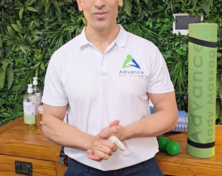 wollongong Massage Therapist in white shirt and green plant wall behind