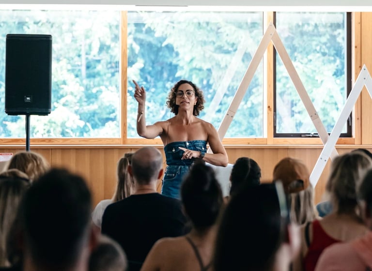 A female motivational speaker at an indoor business workshop event with headset beside speaker
