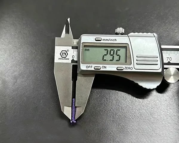 Digital caliper measuring a purple titanium screw showing a 2.95 mm reading on the LCD display | Rui