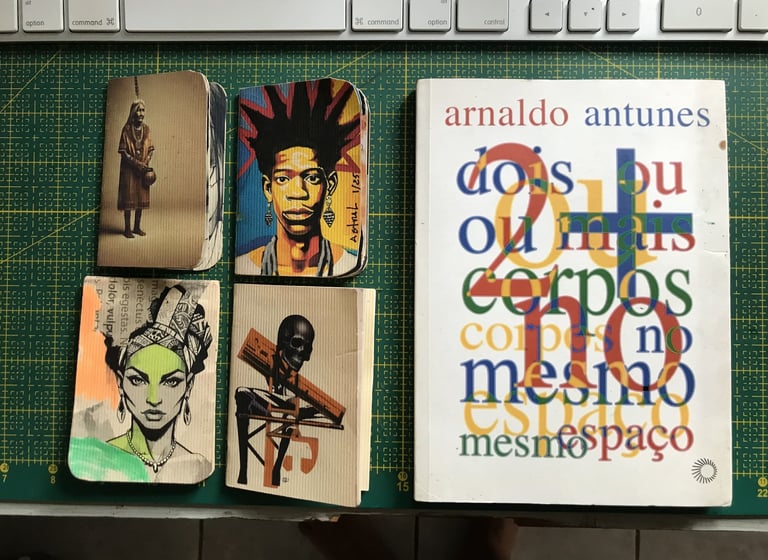 Caderno de artista com anotações e desenhos. Ao lado livro Arnaldo Antunes.