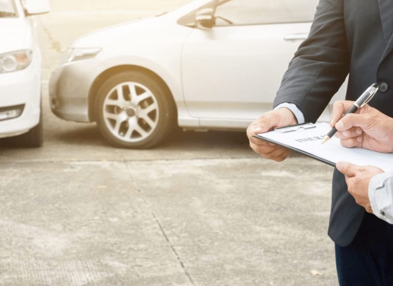 Perito automotriz inspeccionando detenidamente un siniestro de coches, tomando notas