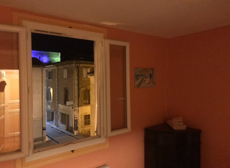 Chambre rustique à Quillan avec murs couleur terre cuite, lit double et fenêtre ouverte 