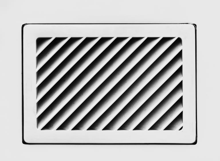 Angled black slats inside a white rectangular vent.