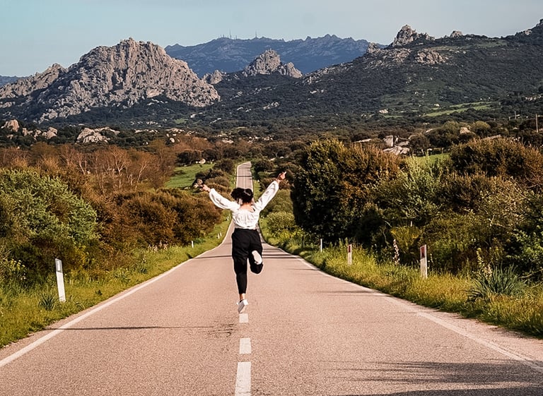 Girl jumping on Valle della Luna panoramic road near Aggius, Sardinia