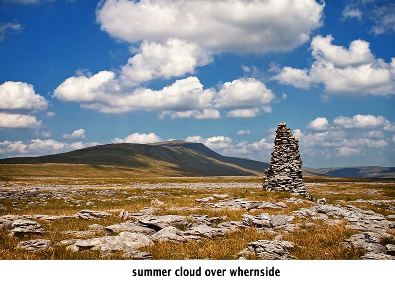 a stone limestone cairn with a whernside fell in the background