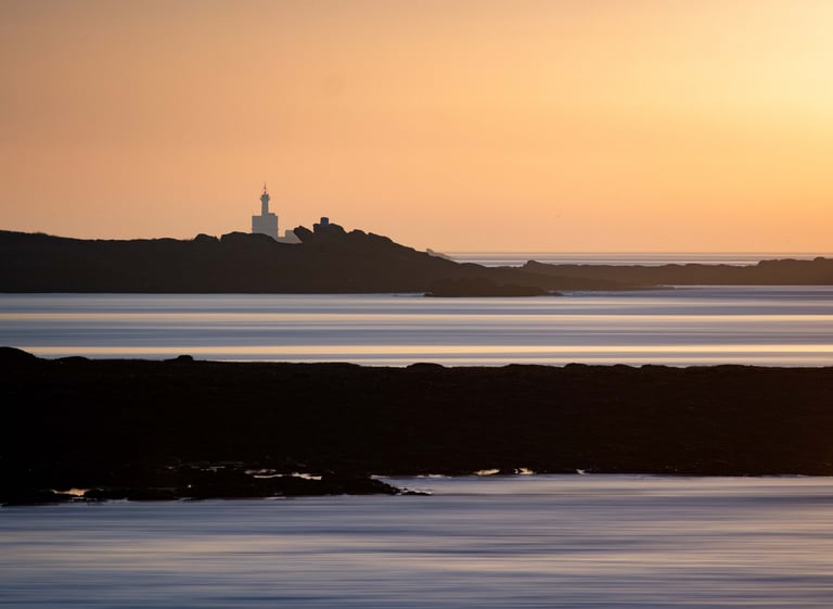 a lighthouse at sunset with a lighthouse in the background