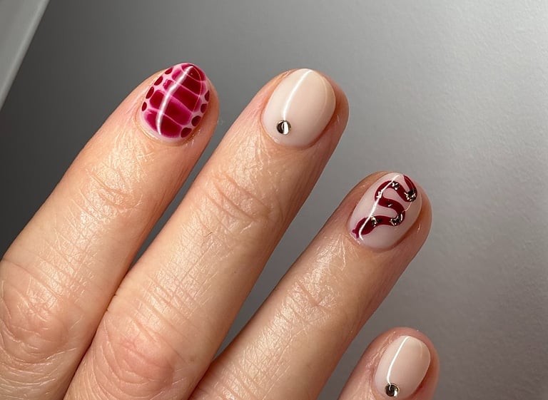 Image of perfectly manicured hands with red nails with patterns in them