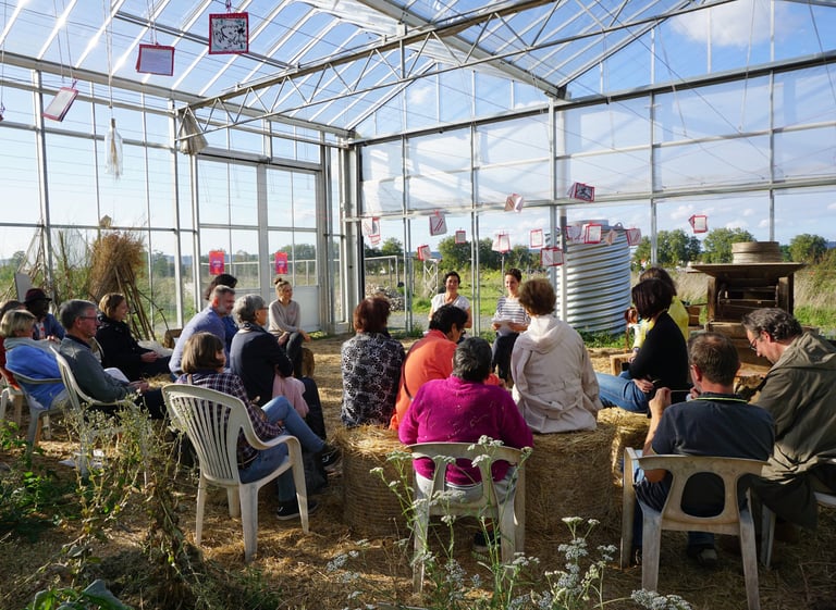 Une foule est assise dans une serre et écoute la conférence sur Vivant et Vivants de la FDW