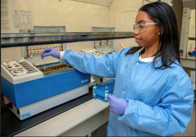 a woman in a lab coat and gloves holding a device