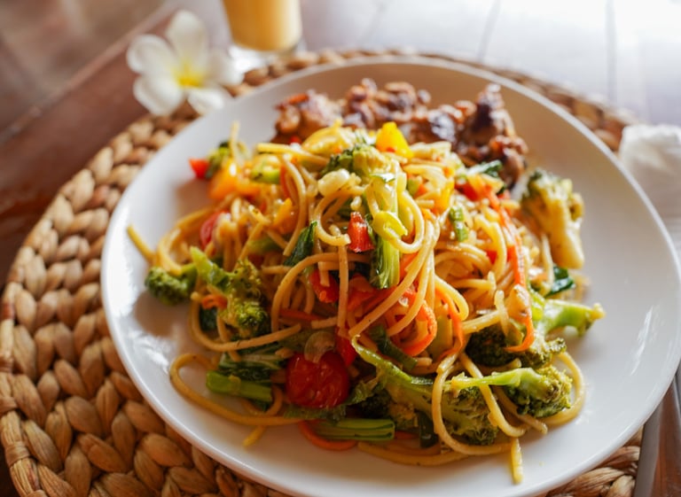 Plate of fresh vegetable pasta with broccoli, tomatoes, and Indonesian spices at Toska Mentawai