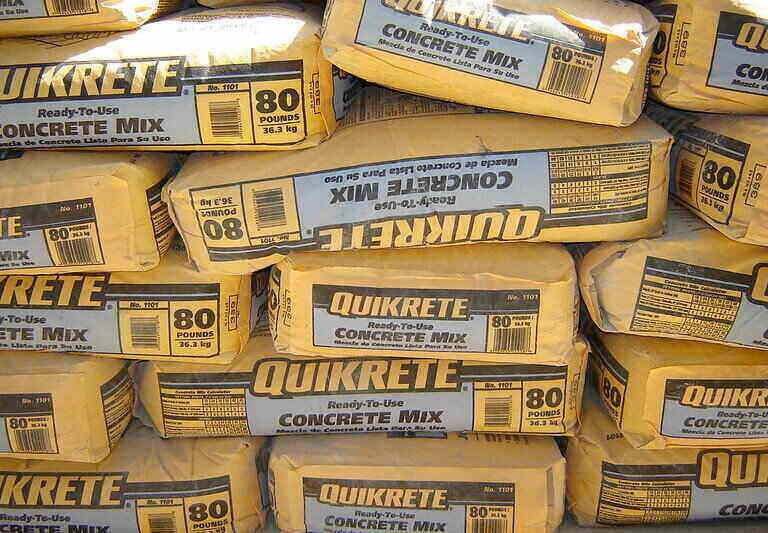 Stacks of 80lb pre-mixed concrete bags ready for a residential post installation project.
