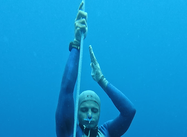 A close up of a Freediver ascending, showing the hands pulling on the dive line