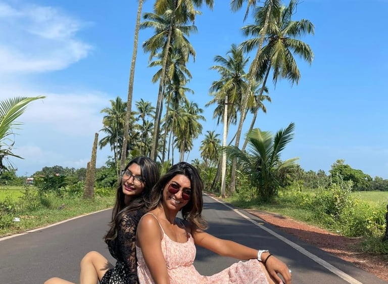 Picture  of 2 sisters siting on the road under Palm trees 