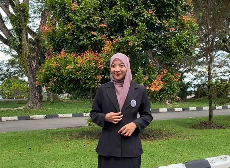 Professional woman wearing a black blazer and pink hijab standing in a green park.