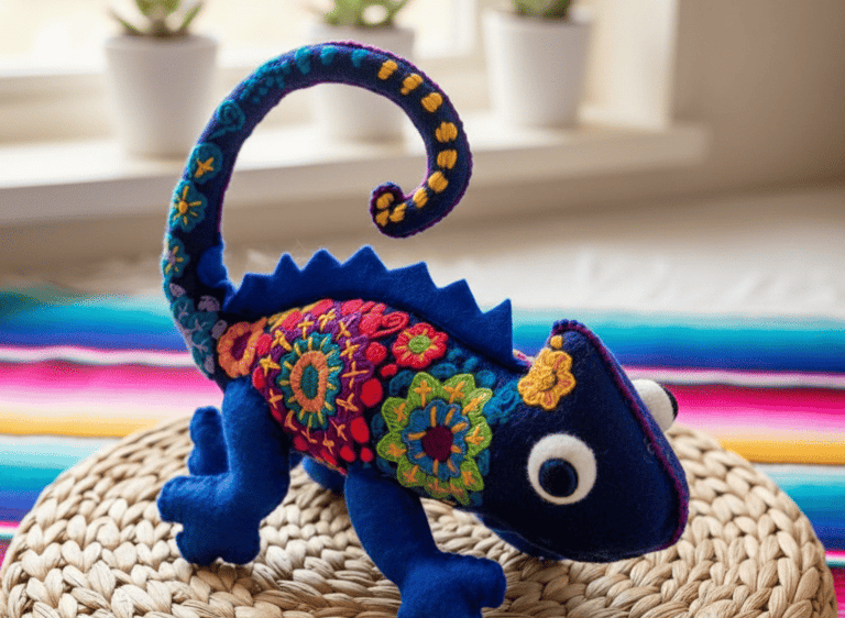 Handmade blue felt chameleon toy featuring vibrant Mexican-style floral embroidery on a woven surface.
