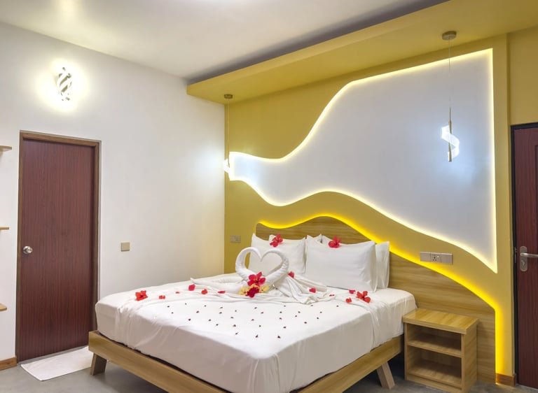 Luxury hotel bedroom with towel swans and rose petals on a bed for a romantic honeymoon suite setup.