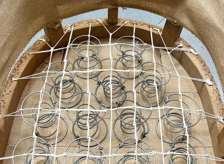 Carcasse d'un fauteuil crapaud avec sur le sanglage des ressorts guindés par des cordes