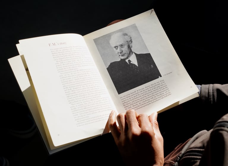 a person holding a book with a picture of FM Alexander