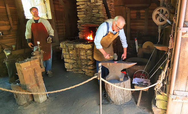 Huntsville, AL - Living history: the blacksmith hammers hot steal into a hook for the barn