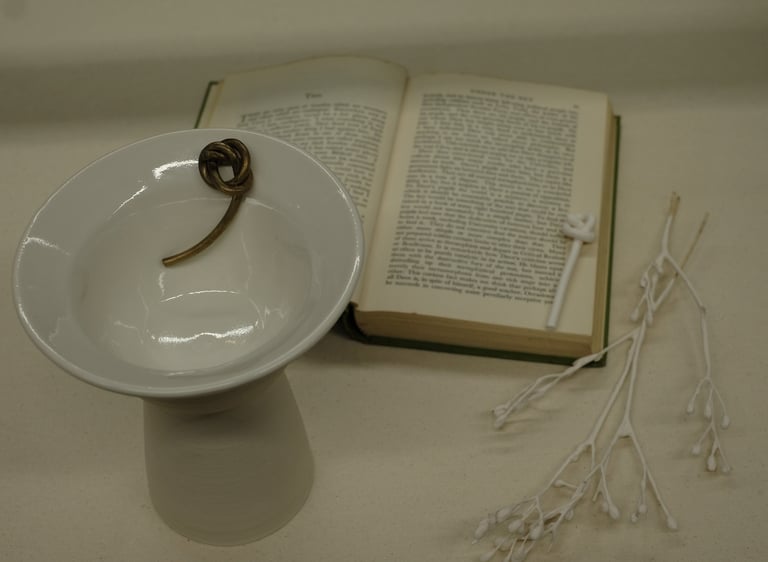 Assemblage including a porcelain vessel with sculptural bronze knot detail and Iris Murdoch novel 