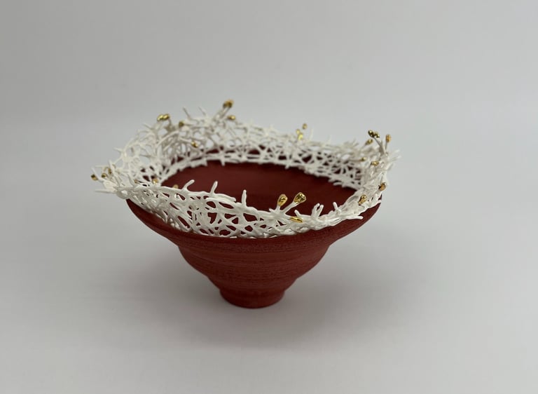 A thrown stoneware ceramic tiered bowl, topped with a porcelain white crown sculpture, tipped gold