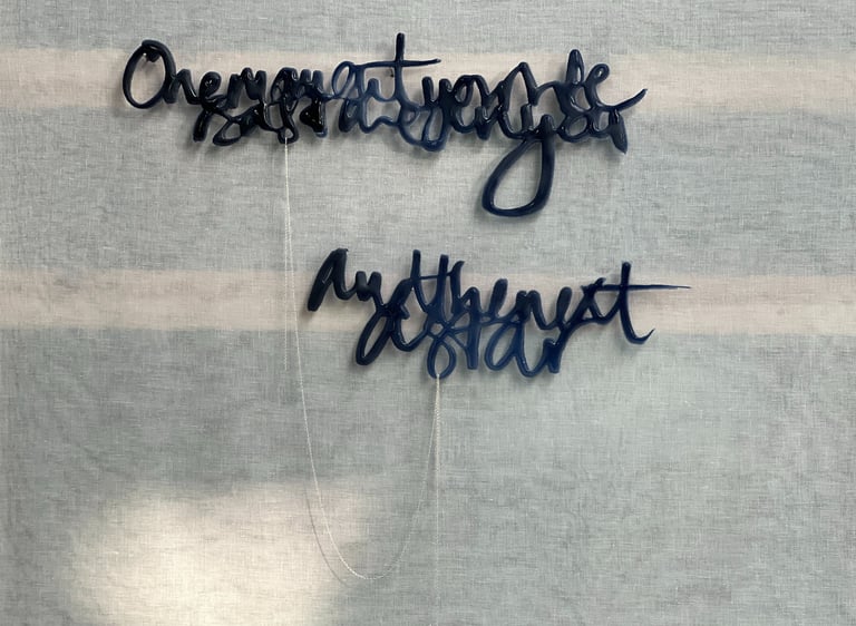 Two lines of semi-abstract text, made in glass and joined by a silver rope chain.