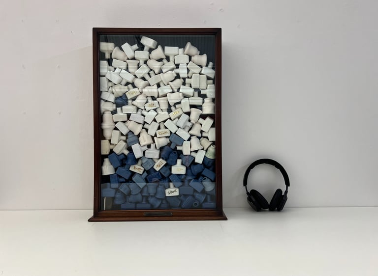 A vintage glazed cabinet holds a stack of 100 small ceramic bottles in blue and white porcelain.