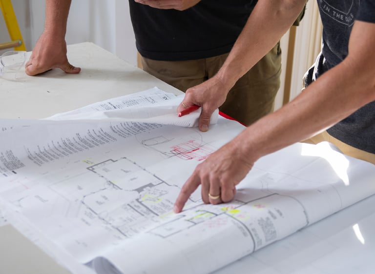 a man and woman are looking at a blueprinted plan