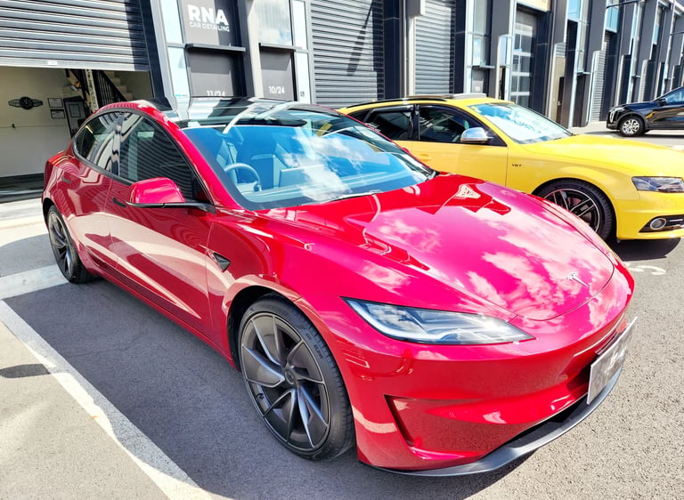 A shiny red Tesla Model 3 electric car parked outside The Coating Lab Auckland