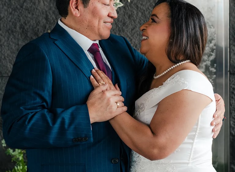 Retrato editorial de novios sonriendo en locación elegante con plantas en Quito. Fotografía documental de bodas premium.