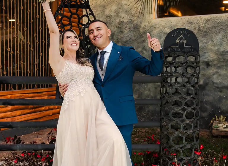 Recién casados celebrando sonriendo a cámara. La novia levanta el ramo y disfrutan de su momento juntos en Quito, Ecuador