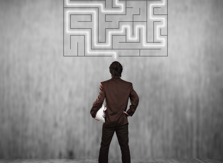 Um homem olha uma parede com um desenho de labirinto e faz um traçado para a saída.