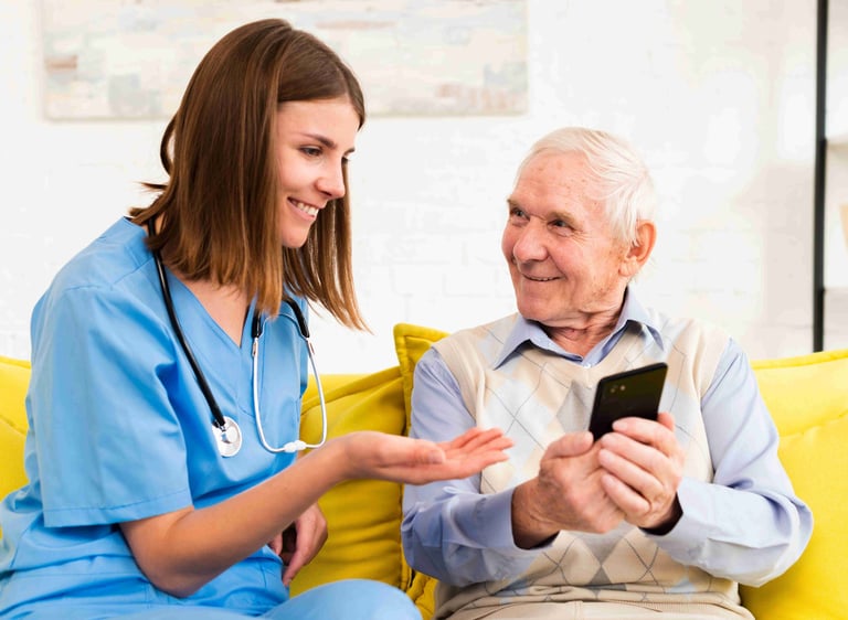 A home care worker attentively reviewing health data on a mobile phone alongside an elderly man.
